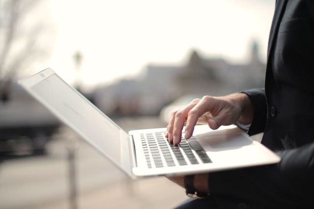 person typing on a laptop in an outdoor setting